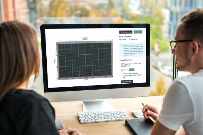 Two people looking at a screen, configuring a solar panel roof